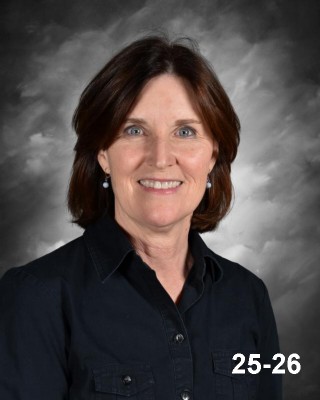 A smiling woman with shoulder-length brown hair, wearing a black shirt, against a gray background.