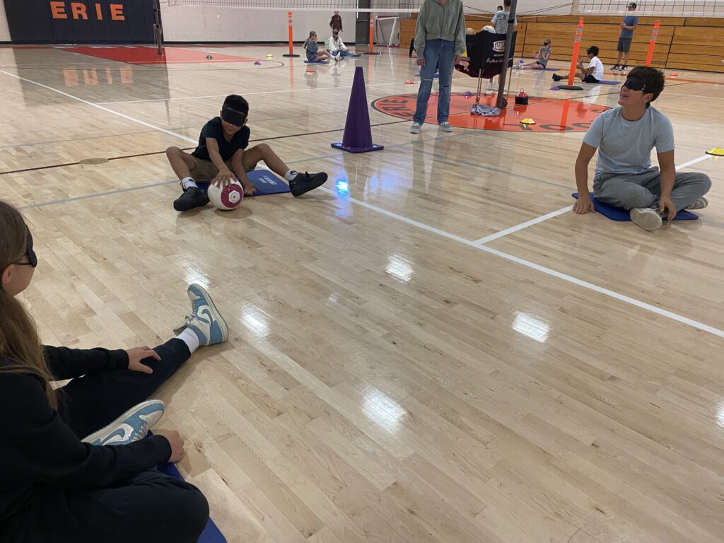 Photo of students playing a game on the gym floor with blind folds