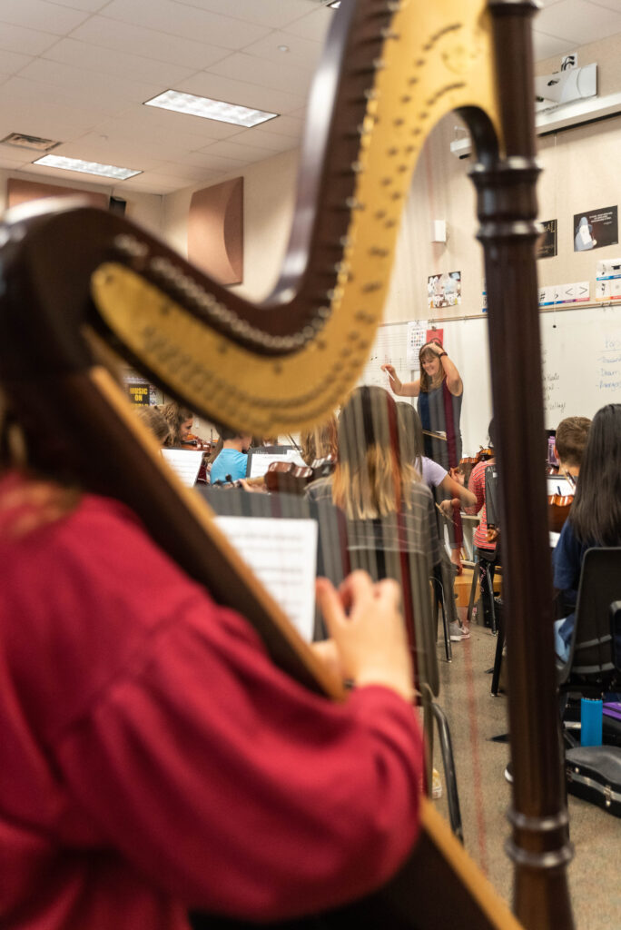 Foto de una clase de banda con primer plano de un alumno tocando el arpa