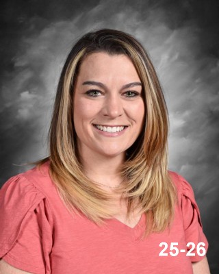 Portrait of a woman with long, straight hair, wearing a coral shirt, smiling against a gray background.