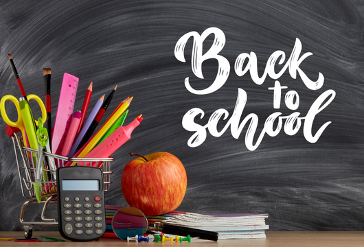 A desk with school supplies: scissors, colored pencils, calculator, an apple, and a chalkboard with "Back to school."