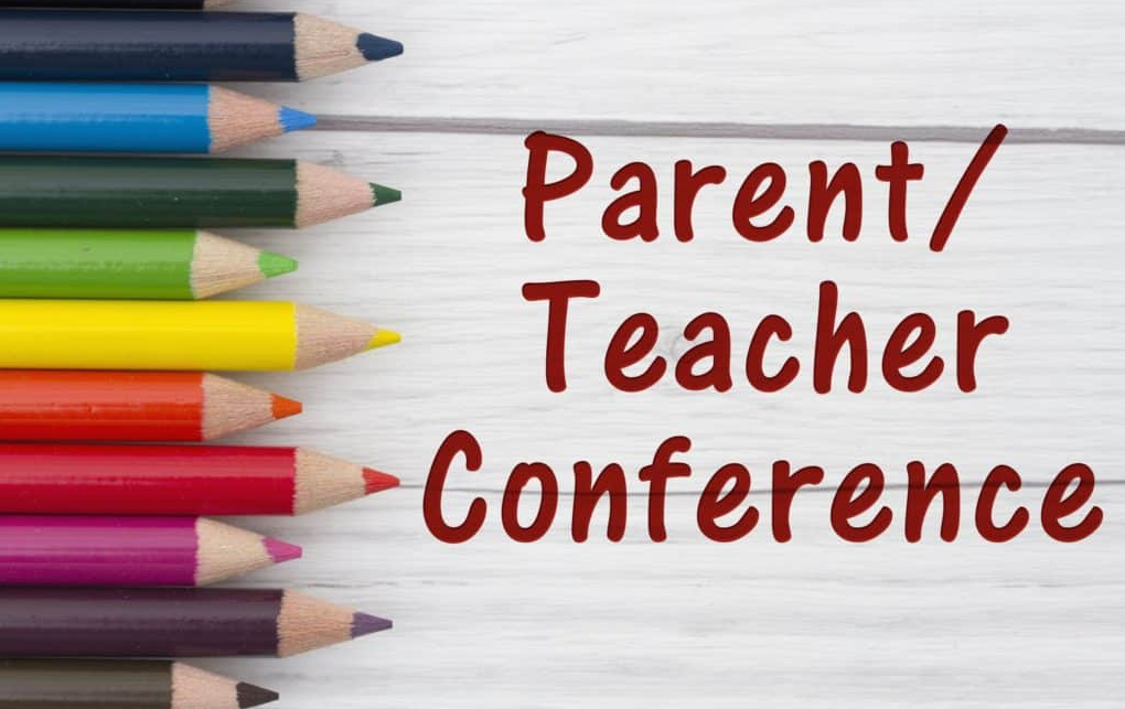 Colorful pencils arranged in a row with the text "Parent/Teacher Conference" on a light wooden background.